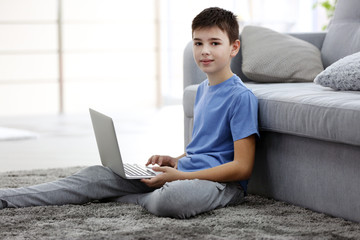 Fototapeta na wymiar Little boy using laptop on a floor at home