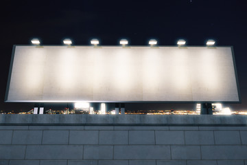 Blank billboard with lights on the top of brick wall at night ci