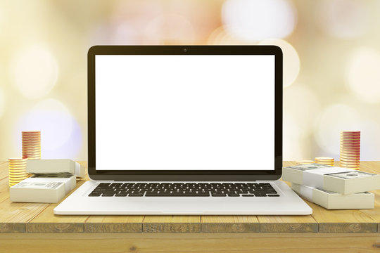 Blank laptop screen on the wooden table with bundles of money an