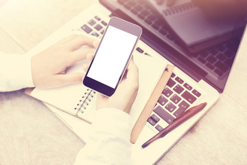 Man hands with blank smartphone screen, diary and laptop on wood