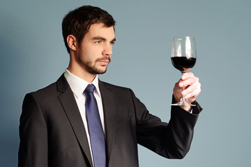 Man looking at the glass of red wine on blue background