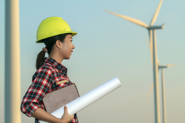 portrait women asia engineer working and holding blueprints at wind turbine farm Power Generator Station