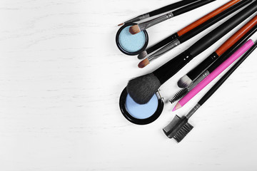 Makeup tools and eye shadows on a light wooden table