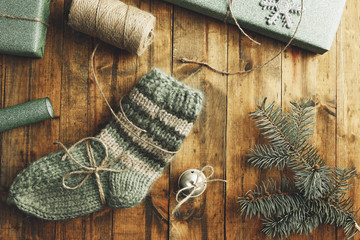 Pair of knitted socks with wrapped gifts for Christmas on wooden table