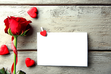 Beautiful rose with gift card on wooden background