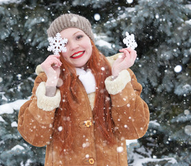 Girl portrait at winter outdoor, snowy weather, showing big snowflake toy.