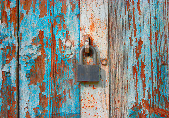 Weathered locked wooden door painted in blue