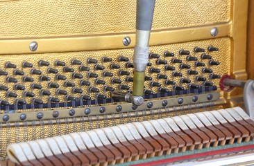 tuner inside of a piano with little hammer