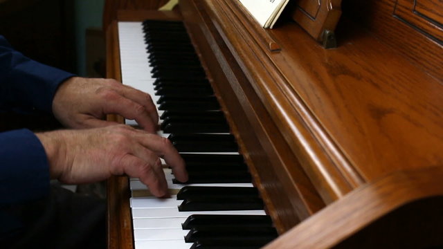 Older Male Hands Playing Piano Viewed From Side
