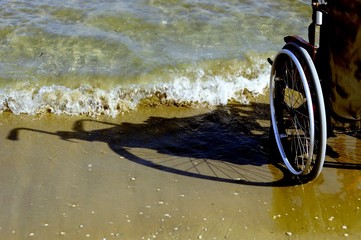 Fototapeta na wymiar shadow of a wheelchair in the sand on the seashore