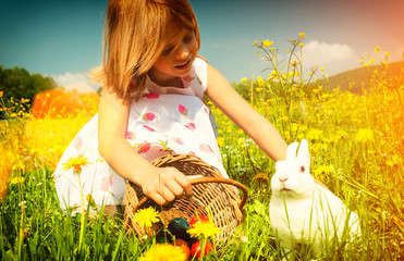 Mädchen streichelt Osterhasen zu Ostern auf Wiese