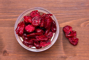 Dried cranberries on bowl on wooden table seen from above