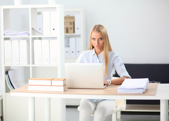 Attractive businesswoman sitting on a desk with laptop in the office
