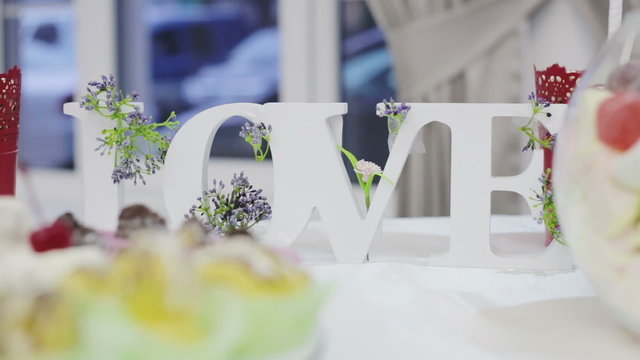 Decor wedding ceremony word love on the bank on the background of flowers 