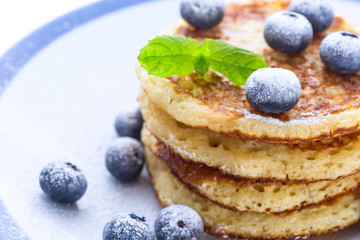 Pile of pancakes with blueberries sprinkled with icing sugar