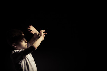 Boy Looking Up While Covering Light Against Black