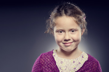 Studio portrait of adorable smiling girl with curly hair on dark background