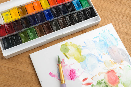 Watercolor half-pan paints palette set on wooden background