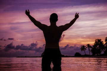 Silhouette of happy man on vacation having fun on the beach of tropical island