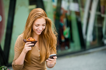 Teenager eating muffin looking in phone