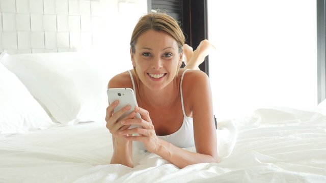 Woman laying in bed and using smartphone