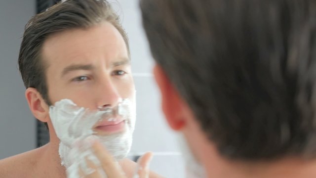Adult man shaving with foam and manual razer