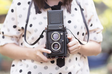 Naklejka premium Woman using vintage camera taking photos in the garden.(Vintage effect style pictures)