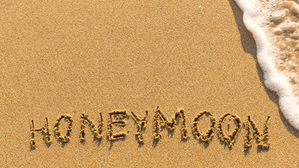 Honeymoon - word drawn on the sand beach with the soft wave.