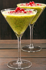 Fresh healthy kiwi drink with pomegranate on wooden background