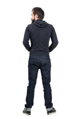 Fototapeta premium Rear back view of bearded man in black hooded sweatshirt looking away. Full body length portrait isolated over white studio background.