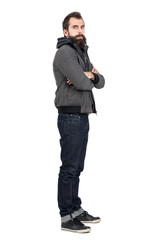 Profile view of bearded man wearing jacket over hooded sweatshirt with crossed arms looking at...