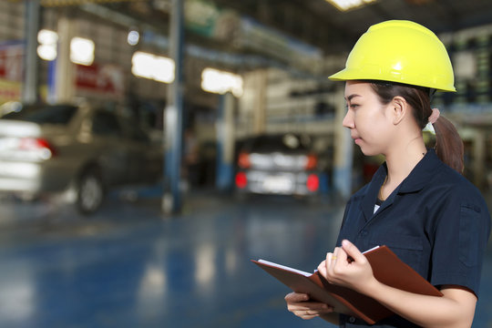 Portrait of smiling young female mechanic inspecting on a car in
