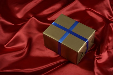 Caja de regalo de color dorado sobre fondo de tela de color rojo