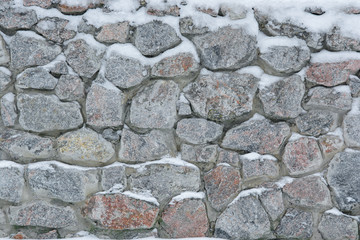 Old stone granite wall in the snow