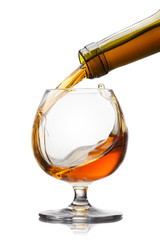 Cognac pouring into glass with splash isolated on white backgrou
