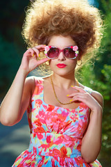 Portrait of young fashion woman in pink dress and hairstyle in park.