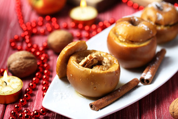 Baked apples on plate on red wooden table