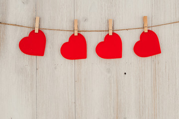 Red heart hanging on the clothesline. On old wood background