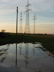 Strommasten spiegeln sich im Wasser