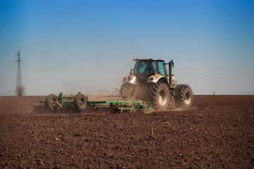 Fototapeta premium view of tractor seeder sowing in ploughed field 
