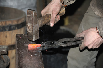 Blacksmith forges a red-hot metal hammer
