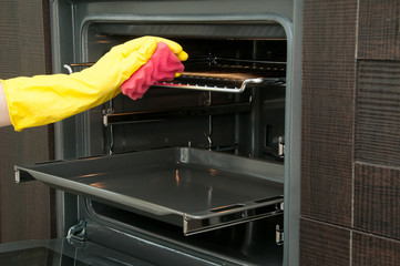 Close up of woman cleaning oven at home kitchen