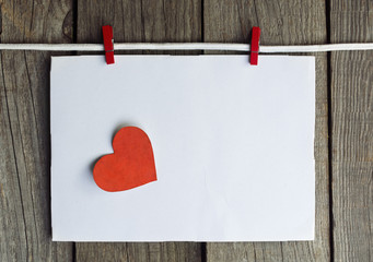 envelope with red heart hanging on the clothesline. On old wood background. Happy Valentines day space for text. toned image