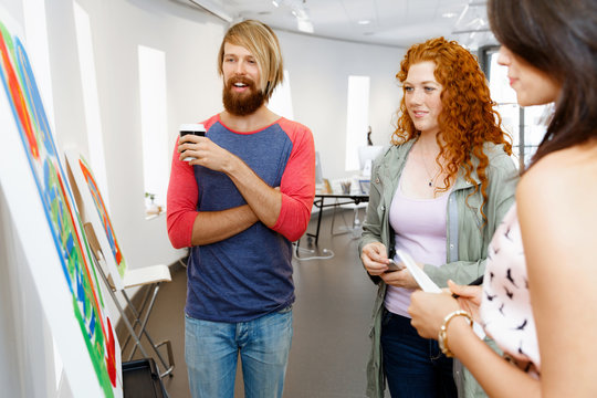 Young people standing in a gallery and contemplating artwork