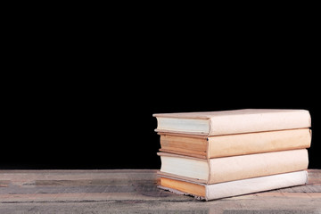 Stack of books on wooden table,  black background