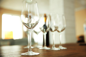Empty wine glasses with bottle on wooden table against blurred background