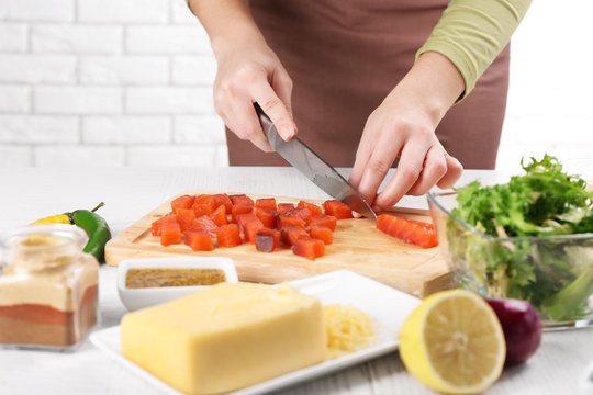 Woman cutting smoked salmon for salad, at kitchen