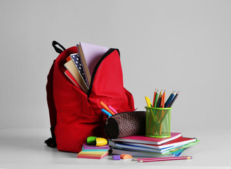 Backpack with school supplies on wooden table