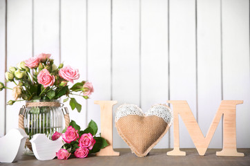 Wooden letters with heart and flowers on white wall background