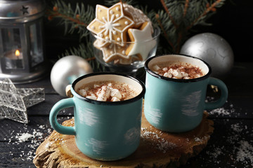 Two mugs of hot cacao with marshmallow and cookies on black table